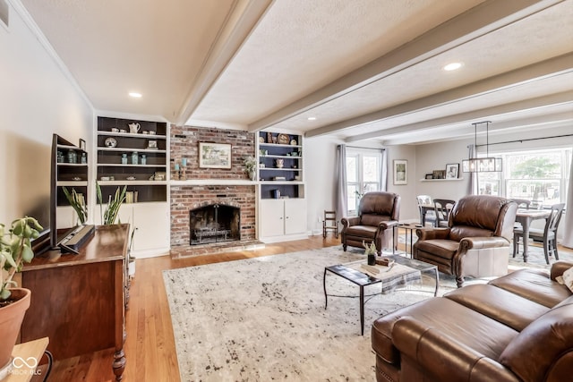 living room with a fireplace, beam ceiling, a textured ceiling, light wood-type flooring, and built in shelves