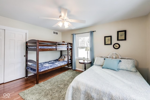 bedroom with dark wood-type flooring, ceiling fan, and a closet