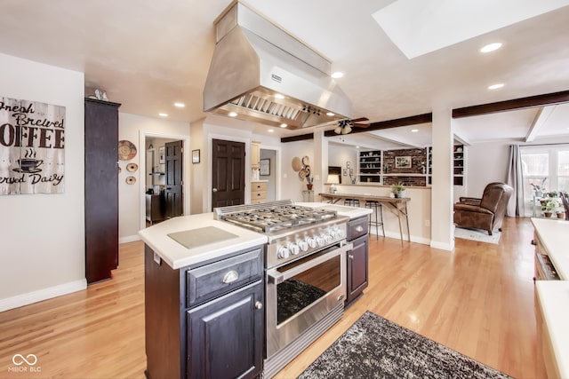 kitchen with ceiling fan, high end range, a center island, extractor fan, and light wood-type flooring