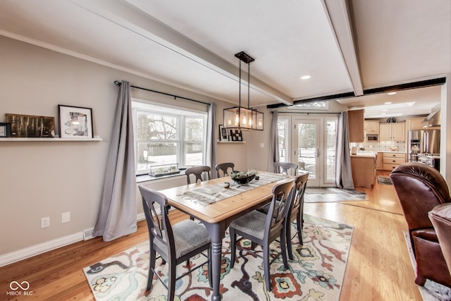 dining room featuring beamed ceiling, crown molding, and light wood-type flooring