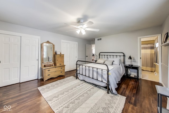 bedroom with two closets, dark wood-type flooring, and ceiling fan