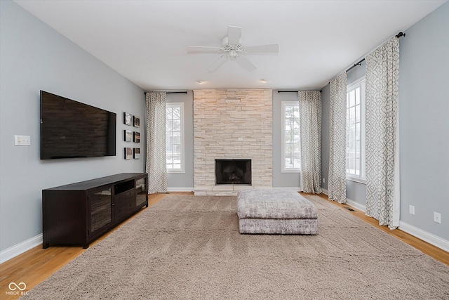 living room featuring a fireplace, ceiling fan, and light wood-type flooring