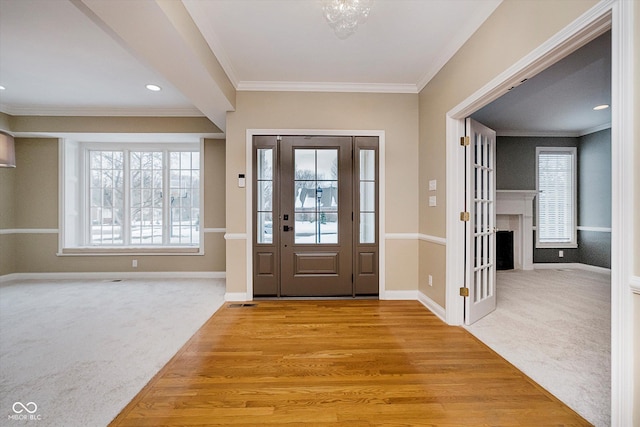 carpeted foyer entrance featuring crown molding and plenty of natural light