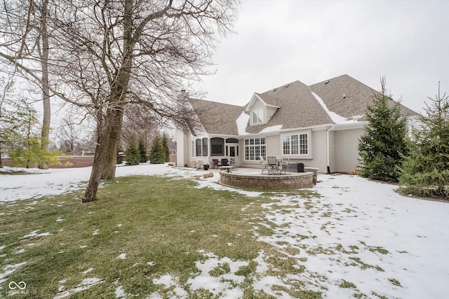 snow covered rear of property with a yard and a patio area