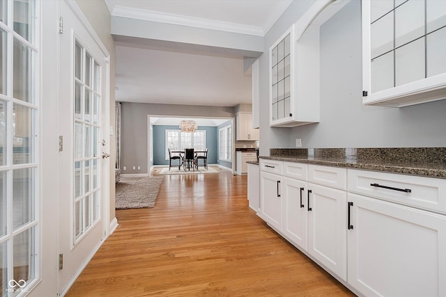 kitchen with white cabinetry, dark stone countertops, a chandelier, light hardwood / wood-style floors, and crown molding