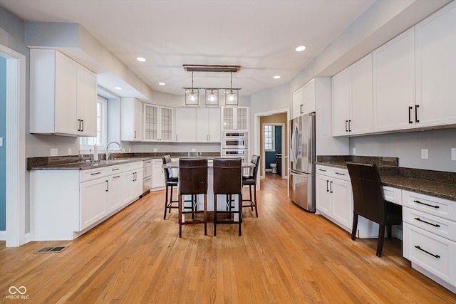 kitchen featuring built in desk, white cabinetry, a kitchen bar, a center island, and stainless steel appliances