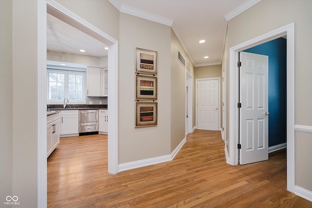 hallway with crown molding, sink, and light hardwood / wood-style flooring