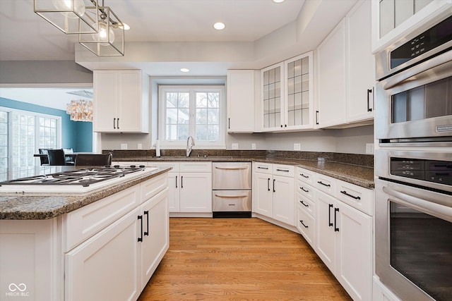 kitchen with sink, white cabinetry, dark stone countertops, light hardwood / wood-style floors, and white gas cooktop