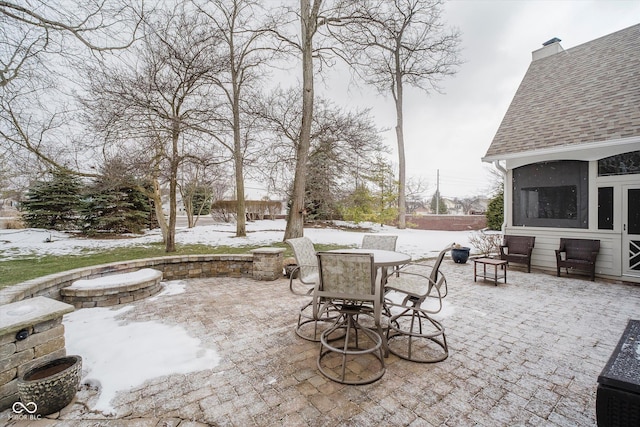 snow covered patio with an outdoor fire pit