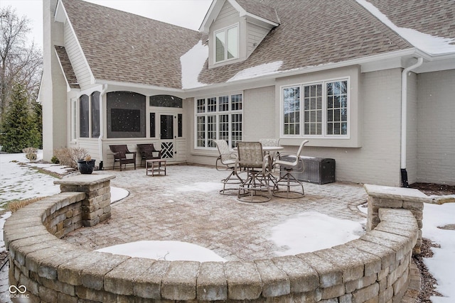 snow covered rear of property featuring a patio