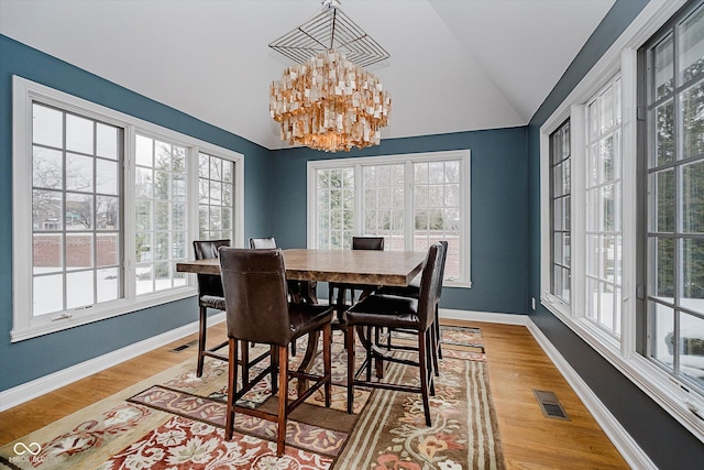 dining area with vaulted ceiling, a chandelier, and hardwood / wood-style floors