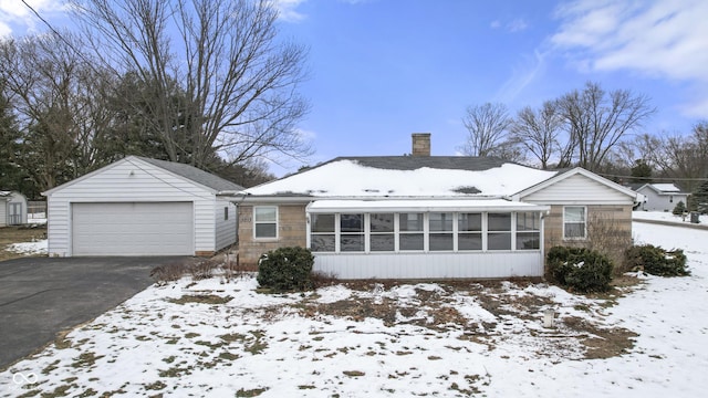 view of front of house with a garage, an outdoor structure, and a sunroom