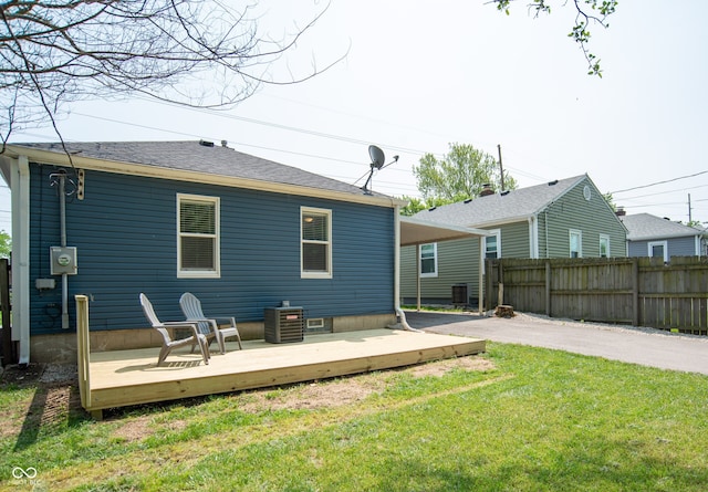 back of property with a lawn, a deck, and central AC