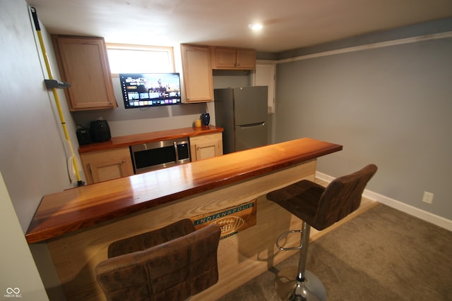 kitchen with fridge, light brown cabinetry, and wooden counters