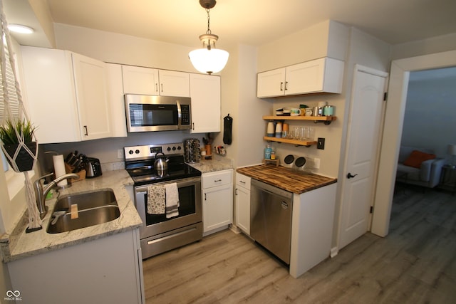 kitchen featuring white cabinets, decorative light fixtures, stainless steel appliances, and sink