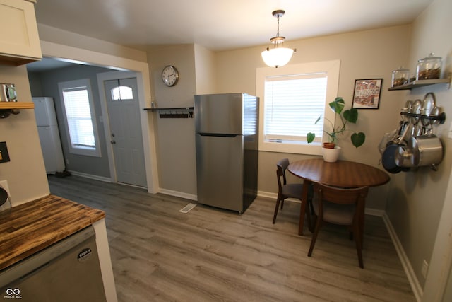 kitchen featuring white cabinetry, hardwood / wood-style flooring, stainless steel refrigerator, white refrigerator, and pendant lighting