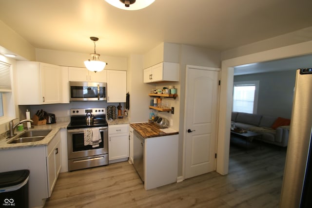 kitchen with sink, appliances with stainless steel finishes, white cabinets, and pendant lighting