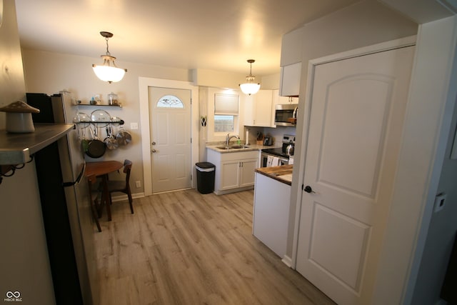 kitchen featuring white cabinets, hanging light fixtures, stainless steel appliances, and sink