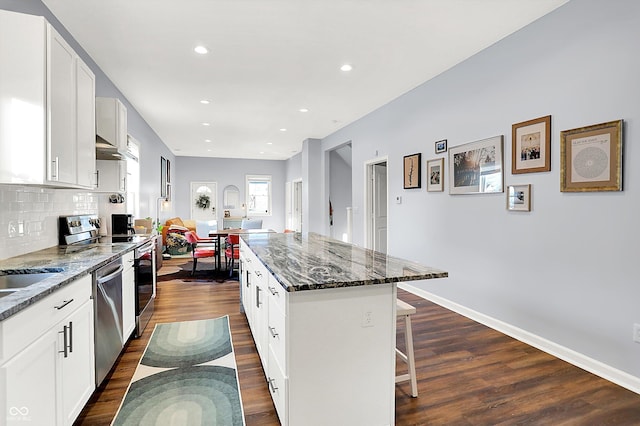 kitchen featuring white cabinetry, appliances with stainless steel finishes, a kitchen breakfast bar, and a kitchen island