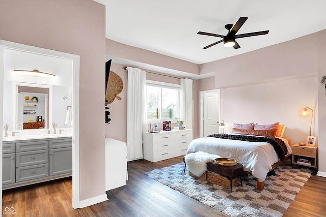 bedroom featuring dark wood-type flooring, ceiling fan, connected bathroom, and sink