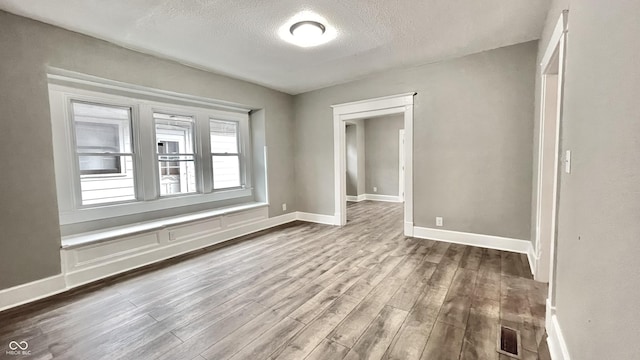 empty room featuring hardwood / wood-style flooring and a textured ceiling