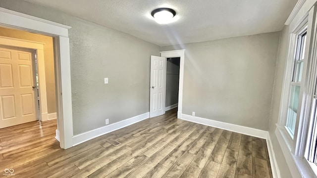 empty room with hardwood / wood-style flooring and a textured ceiling