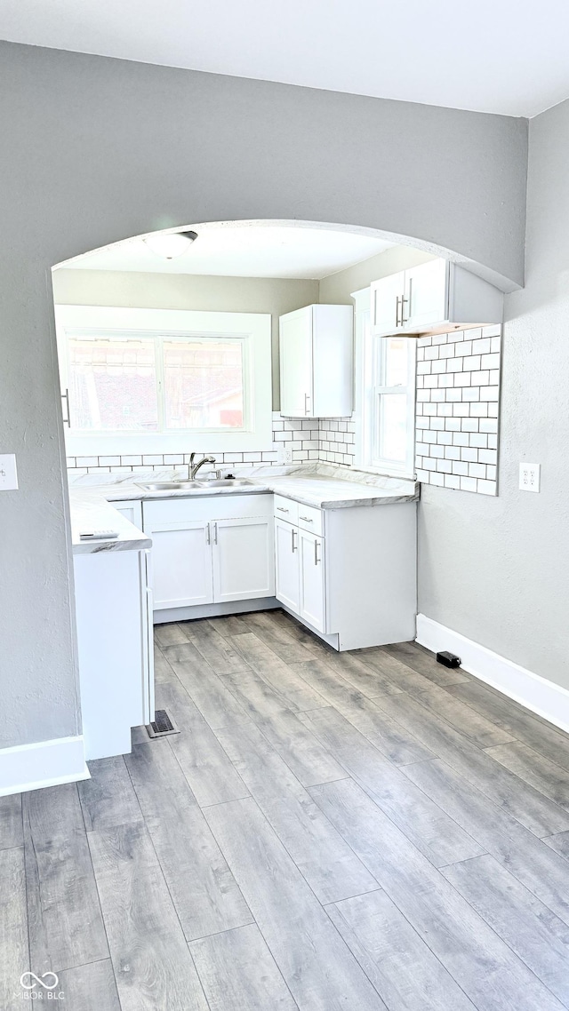 kitchen with sink, light hardwood / wood-style floors, white cabinetry, and decorative backsplash