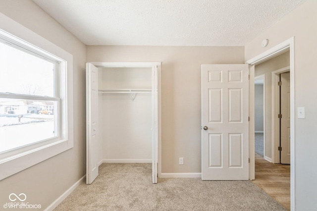 unfurnished bedroom with light colored carpet, a closet, and a textured ceiling