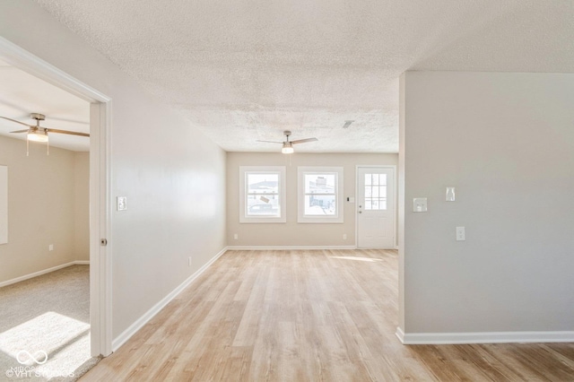 empty room with a textured ceiling, ceiling fan, and light wood-type flooring