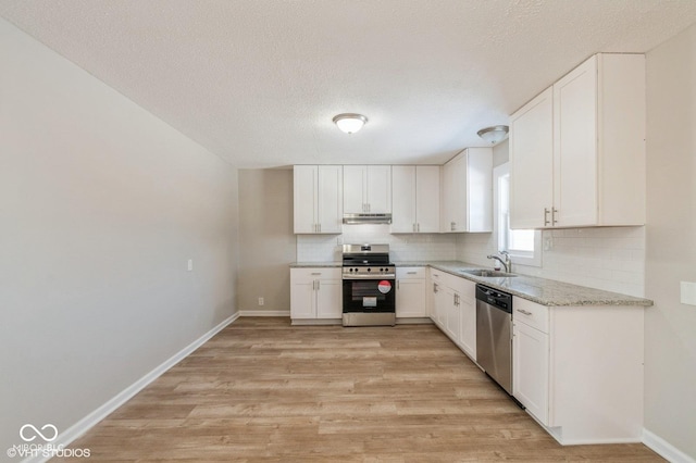 kitchen featuring sink, white cabinets, light hardwood / wood-style floors, stainless steel appliances, and light stone countertops