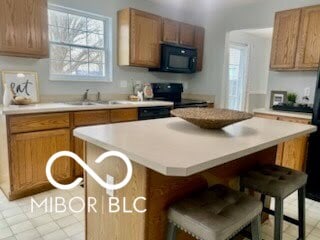 kitchen with a kitchen bar, a center island, sink, and black appliances