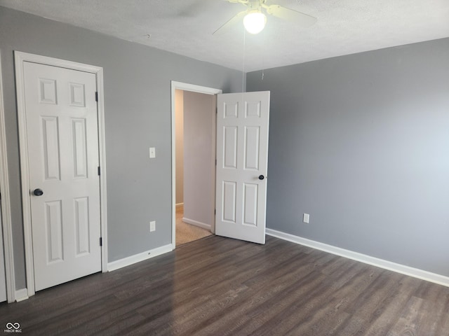 unfurnished bedroom featuring dark hardwood / wood-style flooring, a textured ceiling, and ceiling fan