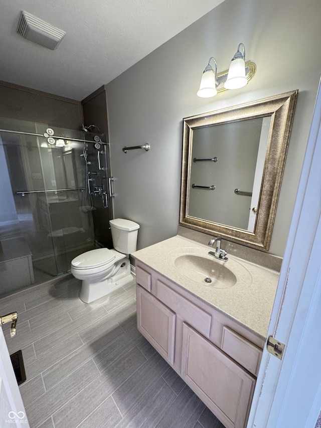 bathroom with a shower with door, vanity, and toilet