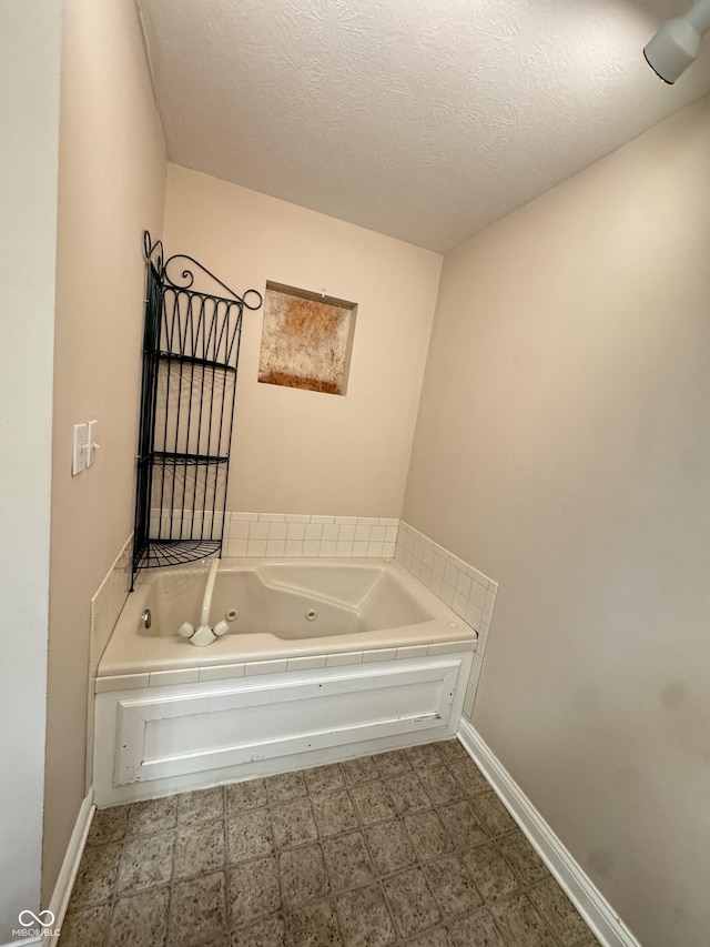 bathroom with a tub to relax in and a textured ceiling