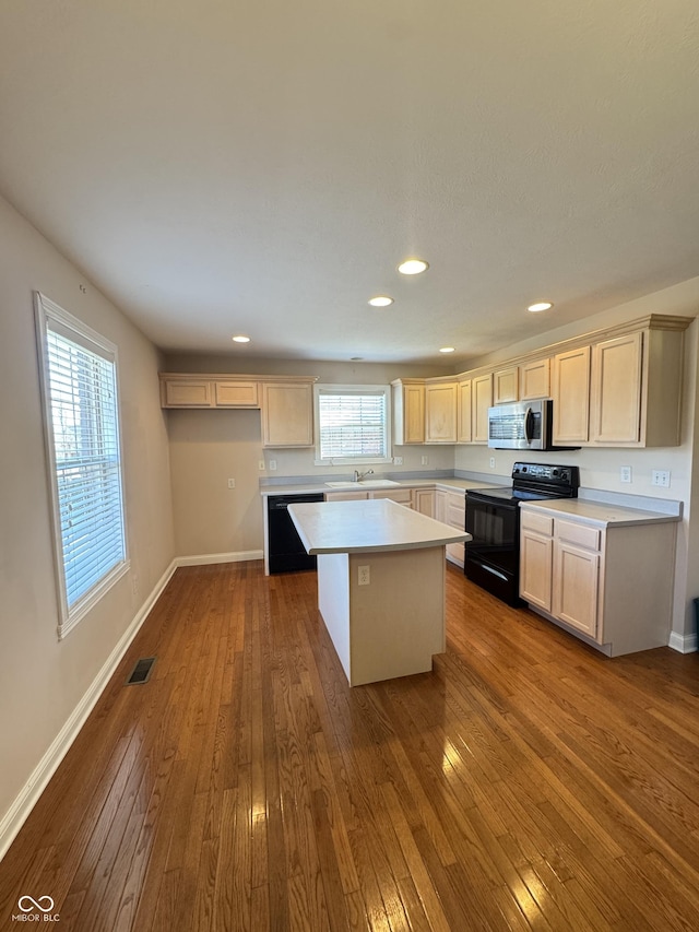 kitchen featuring a center island, sink, dark hardwood / wood-style floors, and black appliances