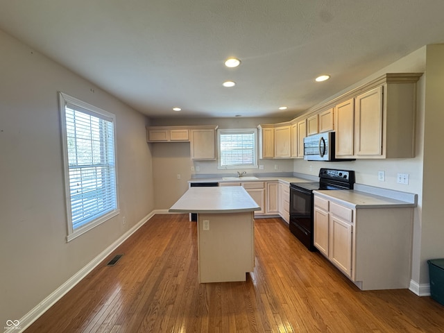 kitchen with light hardwood / wood-style floors, sink, a center island, and black electric range