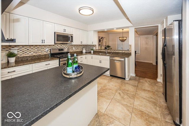 kitchen featuring pendant lighting, white cabinetry, sink, backsplash, and stainless steel appliances