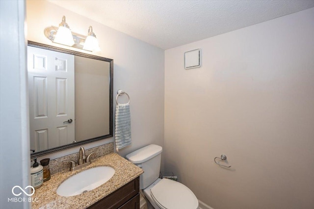 bathroom featuring vanity, toilet, and a textured ceiling