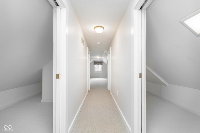 hall with vaulted ceiling and light colored carpet