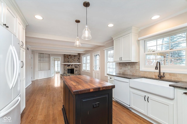 kitchen featuring dishwasher, butcher block countertops, white cabinets, refrigerator, and a center island