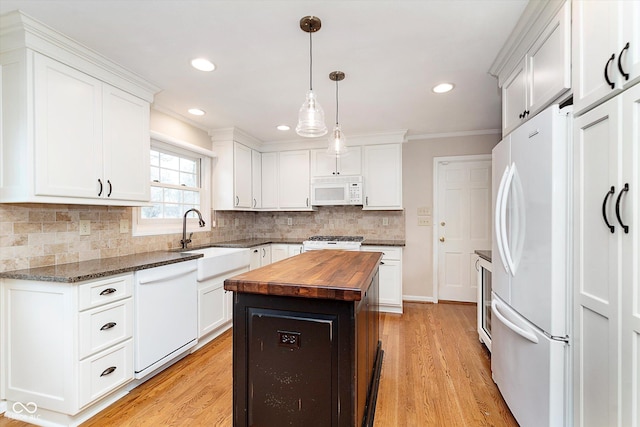 kitchen with white appliances, sink, butcher block counters, a kitchen island, and white cabinets