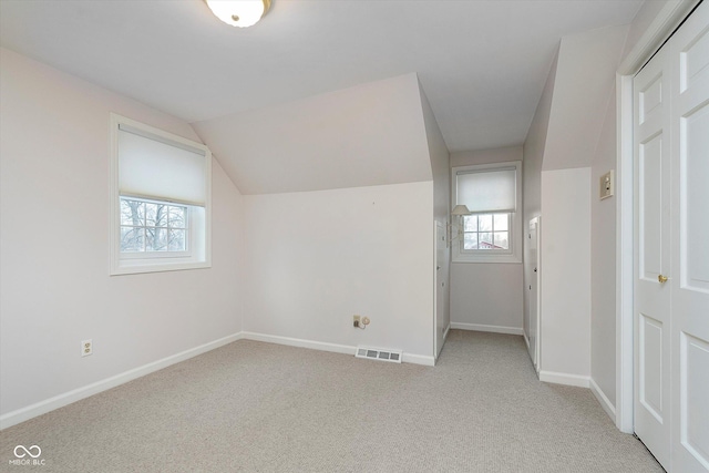 additional living space with vaulted ceiling and light colored carpet