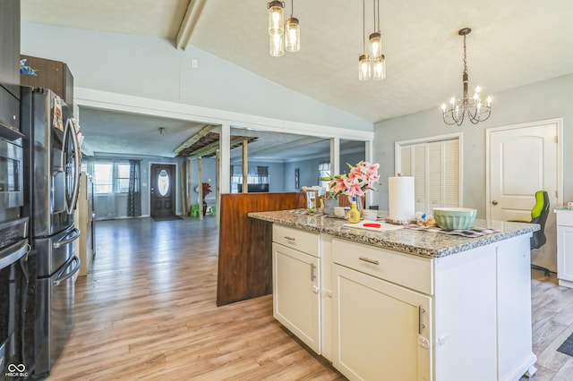 kitchen featuring a kitchen island, white cabinetry, hanging light fixtures, light stone counters, and light wood-type flooring