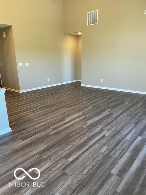 spare room featuring dark wood-type flooring and a towering ceiling