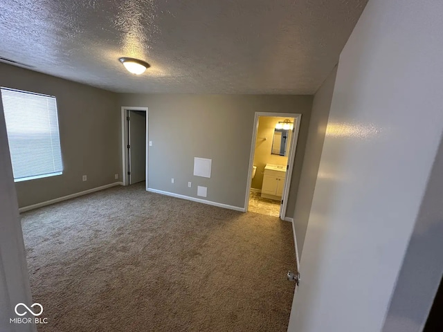 unfurnished bedroom with light carpet, connected bathroom, and a textured ceiling