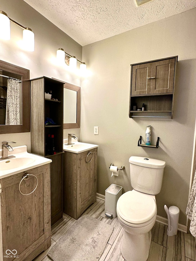 bathroom featuring vanity, toilet, a textured ceiling, and a shower with shower curtain