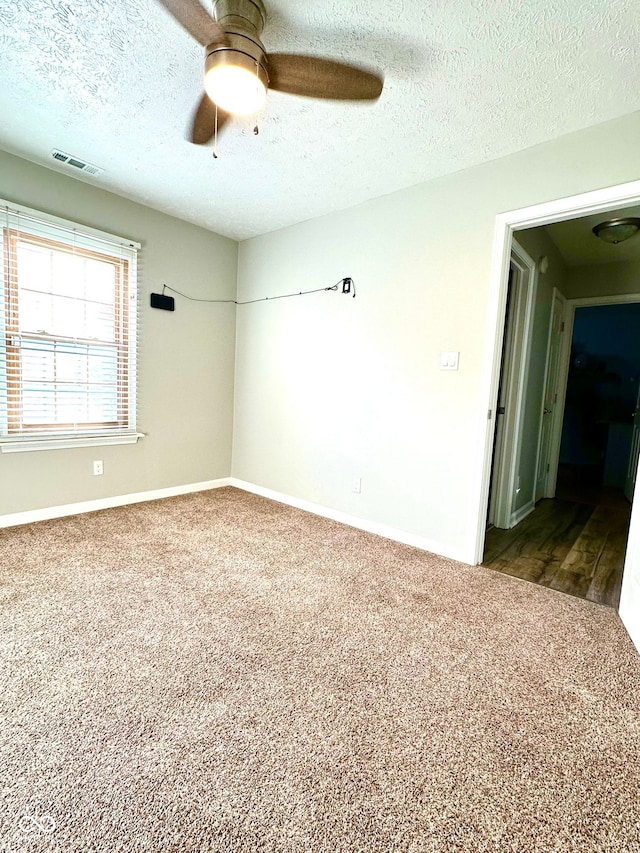 empty room with ceiling fan, carpet floors, and a textured ceiling