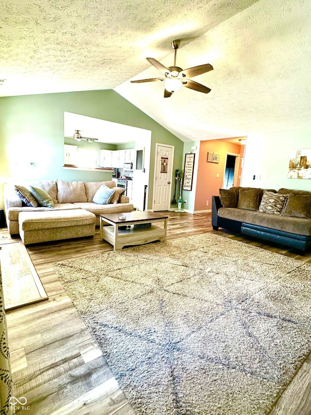 living room featuring hardwood / wood-style flooring, vaulted ceiling, a textured ceiling, and ceiling fan