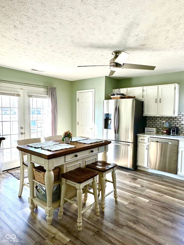 kitchen featuring white cabinetry, tasteful backsplash, light wood-type flooring, ceiling fan, and stainless steel appliances