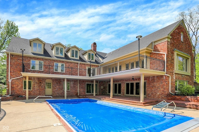 8602 Frontgate Ln, Indianapolis, IN 46256 - rear view of house with a balcony, a patio, a covered pool, brick siding, and a chimney